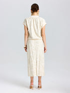 A woman stands with her back to the camera, wearing the Social Queen Floral Embroidered Linen Top, paired with a matching calf-length skirt and high heels.