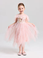 A young girl smiles in a Social Queen Girls Floral Sequin Tulle Dress, light pink and off-the-shoulder, paired with matching pink shoes.