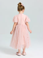 A young girl wears the Social Queen Girls Sequin Embellished Tulle Dress, featuring puff sleeves and a light pink, knee-length tulle skirt, as she stands facing away on a plain background for a dreamy look.