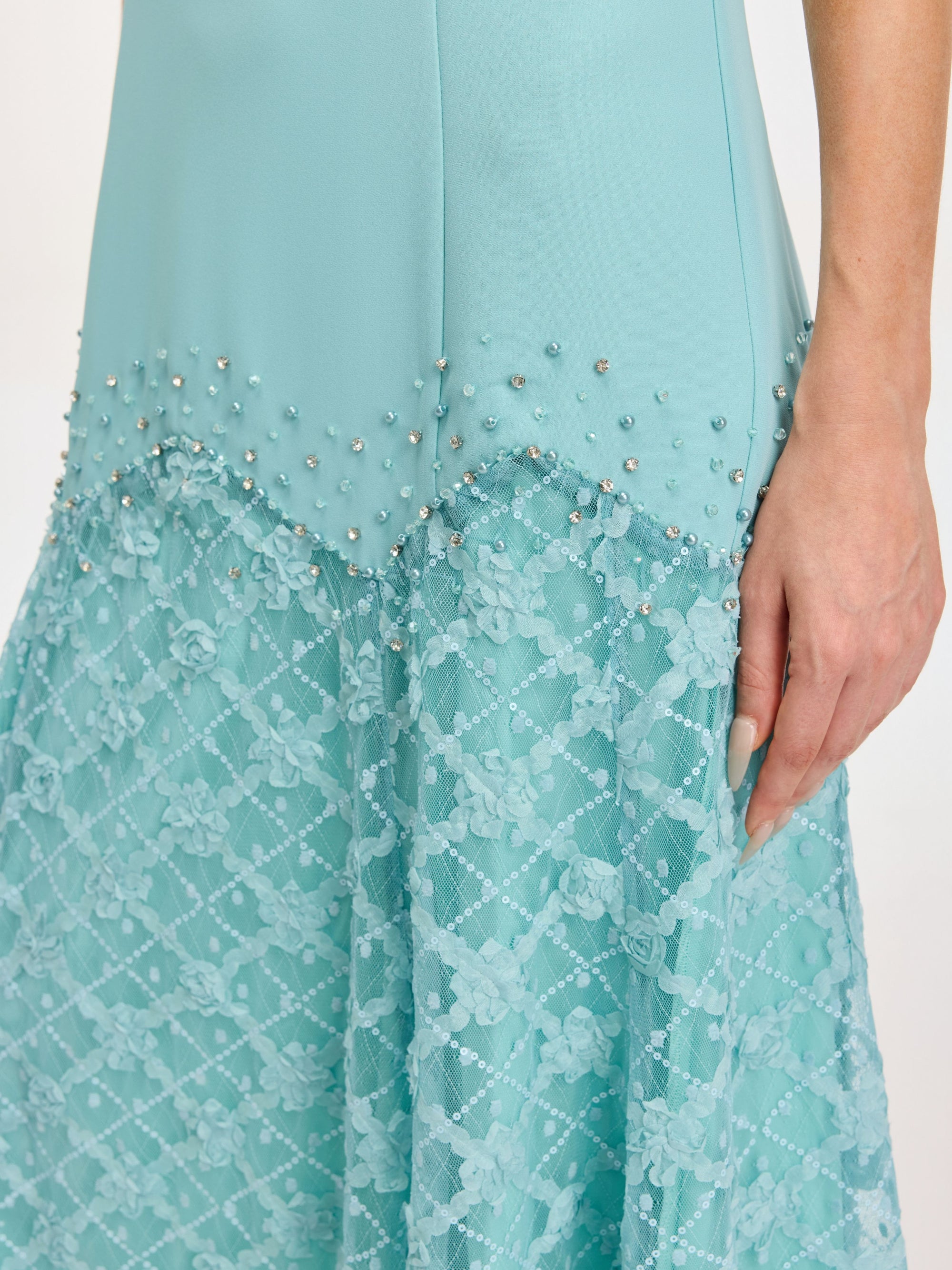 Close-up of the Social Queen Beaded Floral Lace Patchwork Dress in light blue, featuring pearl and bead embellishments at the waist, a floral lace skirt, and a visible hand at the side.