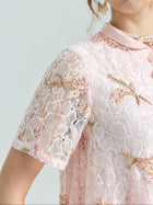 A close-up of a person wearing the Social Queen Dragonfly Beaded Lace Top in pink, featuring gold dragonfly and beaded embroidery, paired with a pearl necklace—an elegant choice for any special occasion.