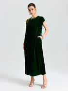 A woman poses in a studio wearing Social Queen's Colorblock Silk Velvet Shift Dress with pockets and gold heeled sandals against a plain background.