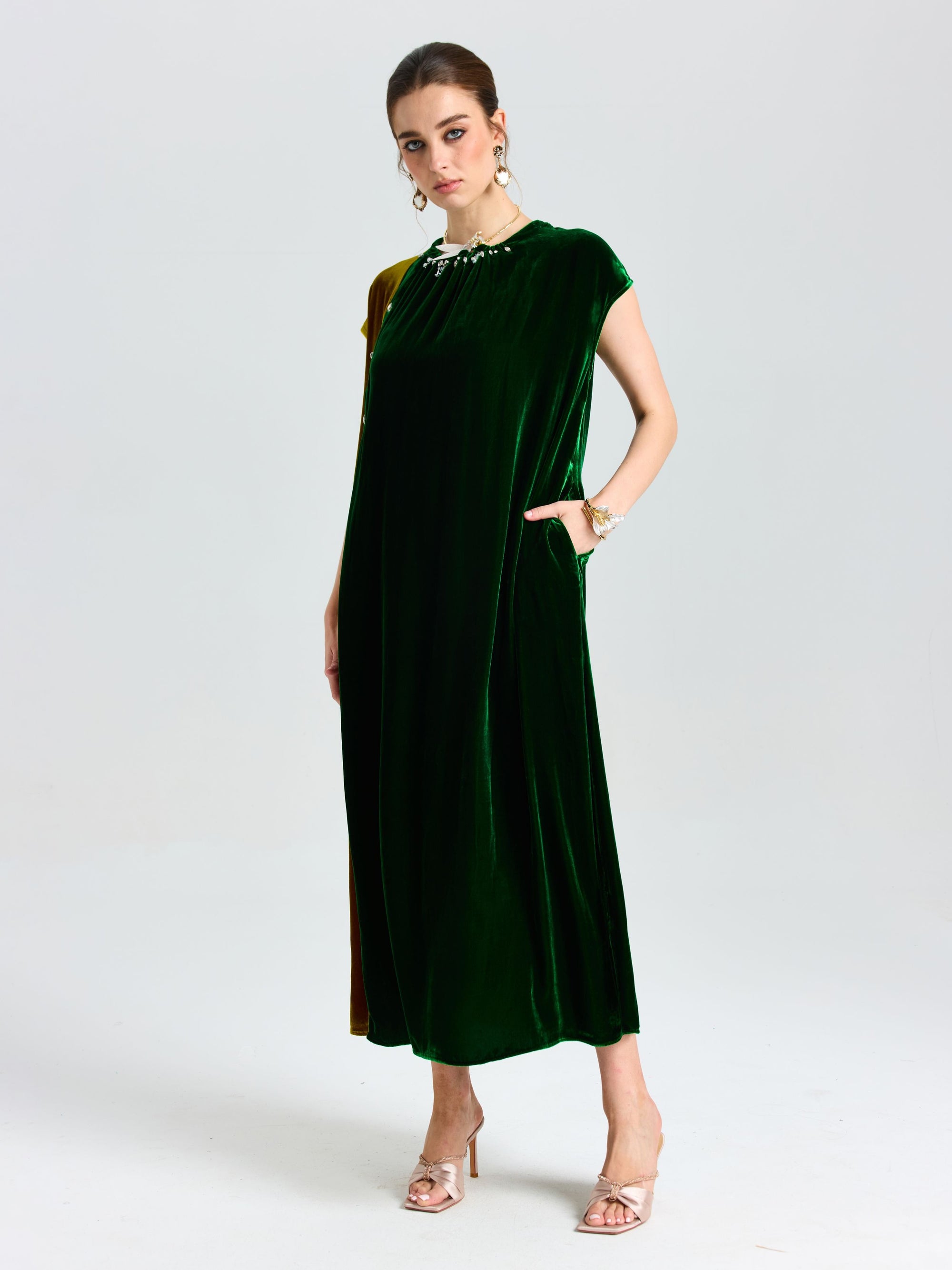 A woman poses in a studio wearing Social Queen's Colorblock Silk Velvet Shift Dress with pockets and gold heeled sandals against a plain background.