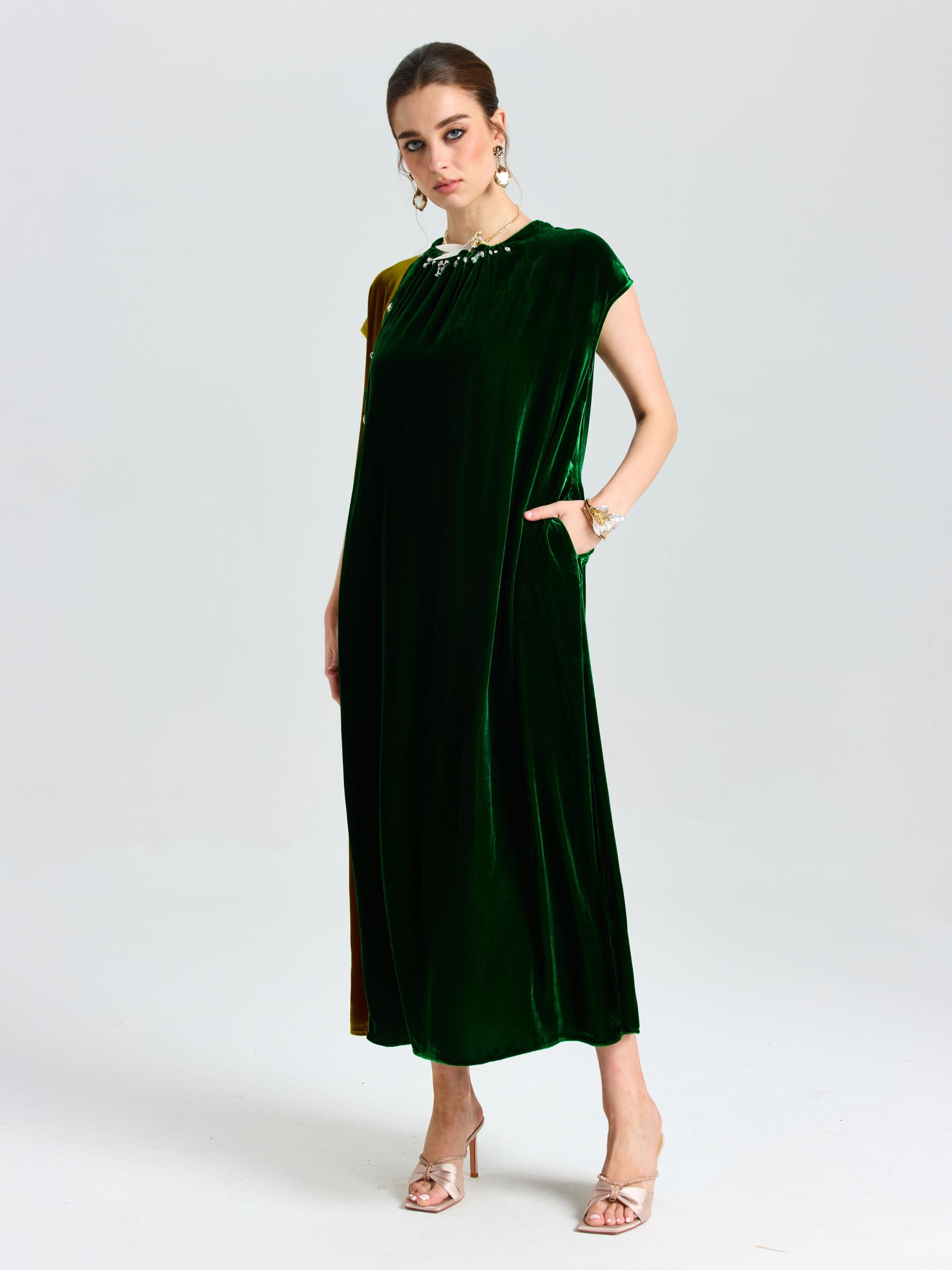 A woman poses in a studio wearing Social Queen's Colorblock Silk Velvet Shift Dress with pockets and gold heeled sandals against a plain background.