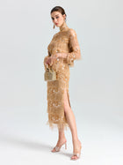 A woman wears the Social Queen Beaded Fringe Slit Midi Skirt and heels, holding a small woven handbag, standing against a plain light background.