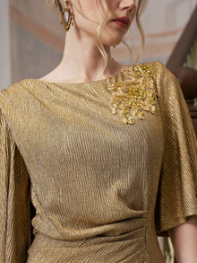 A woman is shown from neck to waist wearing the Social Queen Floral Beaded Knit Dress, which features textured gold beading and a floral embellishment on the shoulder, paired with a large earring.