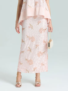 A person wears the Social Queen Dragonfly Beaded Lace Midi Skirt in pale pink with a matching top and holds a small white purse, showing only the lower half of their straight silhouette.