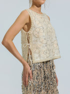 A person is wearing the Social Queen Floral Beaded Mesh Sleeveless Top, styled with a silver and gold sequin skirt, standing against a plain light background.