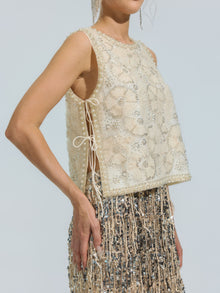 A person is wearing the Social Queen Floral Beaded Mesh Sleeveless Top, styled with a silver and gold sequin skirt, standing against a plain light background.