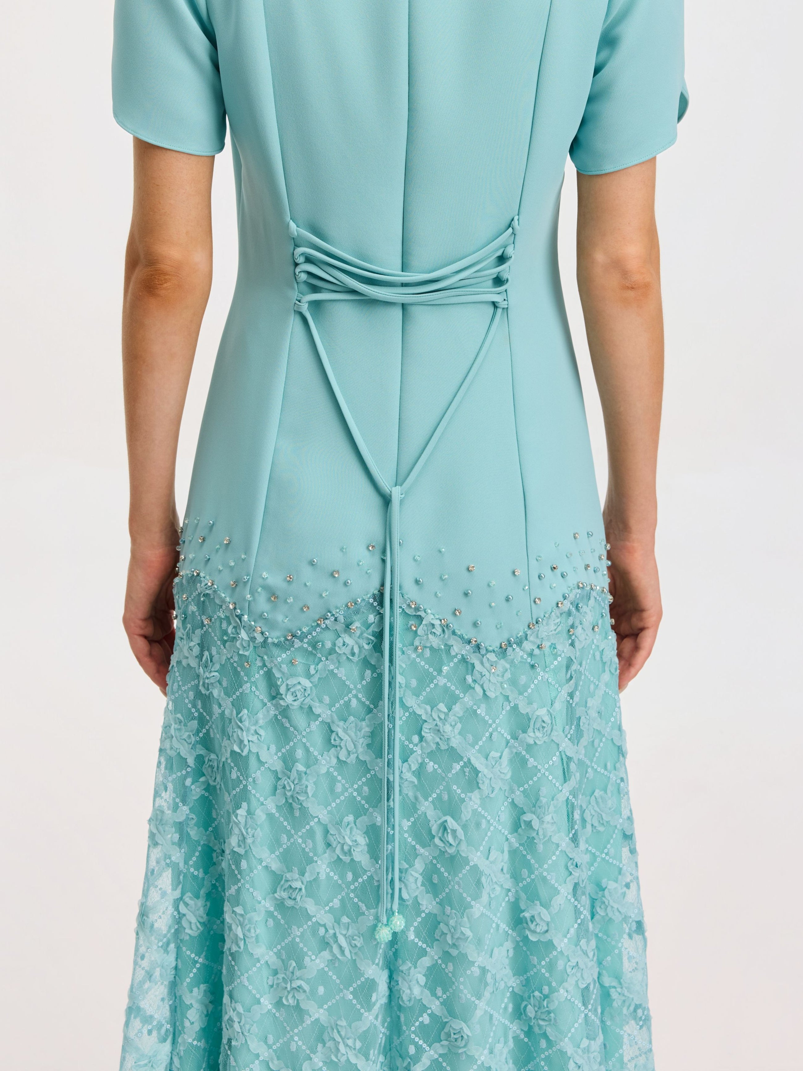 A person wears the Social Queen Beaded Floral Lace Patchwork Dress in light blue, facing away to display the decorative tied cord and intricate lace and bead details.