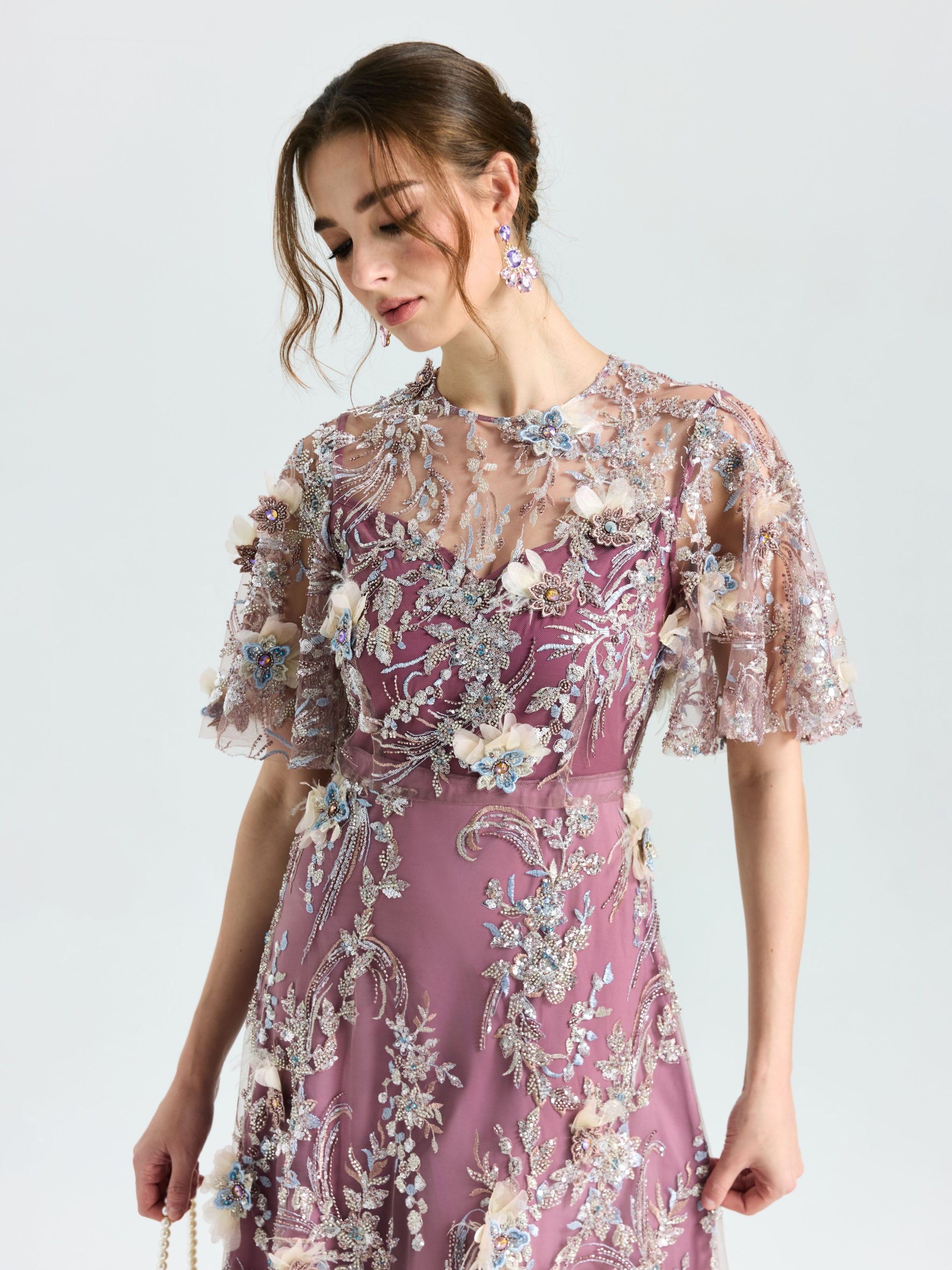 Model wears the Social Queen Floral Beaded A-Line Dress, featuring mauve floral embroidery, sheer embellished sleeves, and delicate details, standing against a plain light background.
