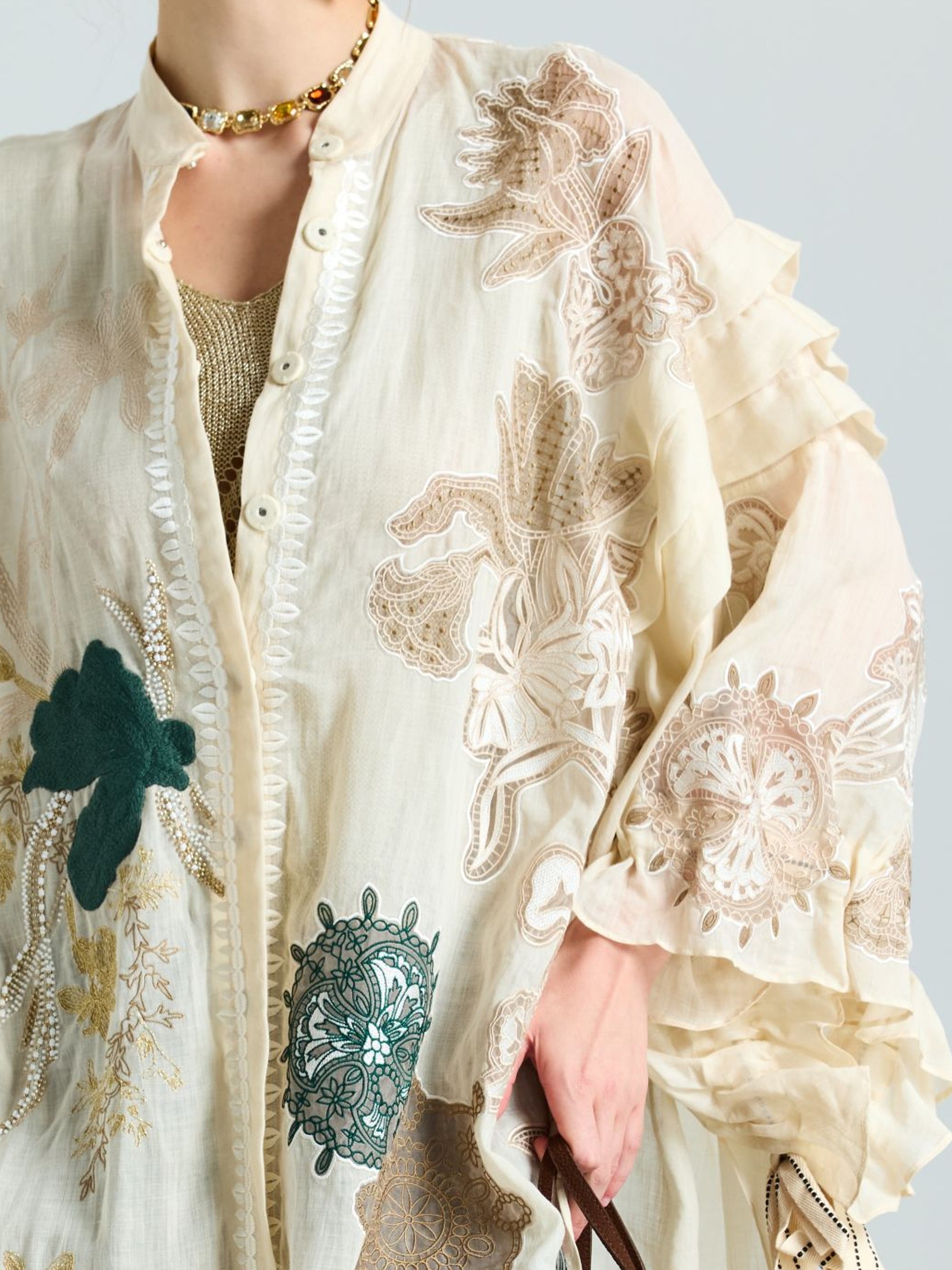 A person wearing the Social Queen Floral Embroidered Linen Jacket (Cami Included), featuring beige, green, and white floral embroidery, accessorized with a gold chain necklace.