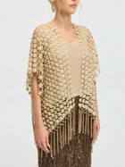A woman wears the Social Queen Pearl Floral Appliqué Fringe Cape—a beige, textured, short-sleeve evening piece with fringe and floral details—over a dark sequined skirt.