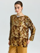A woman wears the Social Queen Flocked Floral Silk Sheer Top (camisole not included), featuring metallic vine-inspired embroidery, paired with gold pants, standing against a plain light gray background.