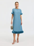 A woman wears the Social Queen Beaded Crystal Embellished Dress with ruffled sleeves and hem, silver heels, statement earrings, and carries a small patterned handbag.
