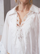 A woman models the Social Queen Floral Cutwork Embroidered Linen Dress, featuring a white design with intricate floral cutwork and a deep, crisscross lace neckline. Only her upper body and part of her face are visible.