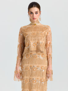A woman faces forward, wearing the Social Queen Beaded Fringe Floral Top, a long-sleeve sheer mesh piece with floral embroidery and sequin embellishments, set against a plain light background.