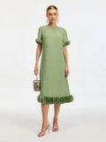 A woman wears the Social Queen Beaded Crystal Embellished Dress, a light green, knee-length shift with ruffled sleeves and hem, crystal accents, and floral details. She carries a handbag and pairs the look with strappy heels.