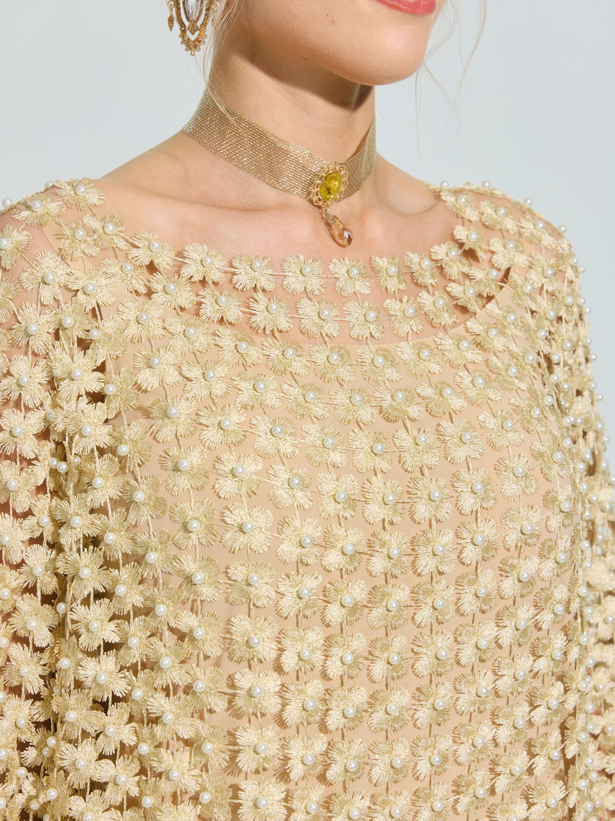 A person wears the Social Queen Pearl Embellished Floral Overlay Dress with 3D floral appliqués and pearl accents, styled with a gold choker necklace featuring a small yellow gemstone.