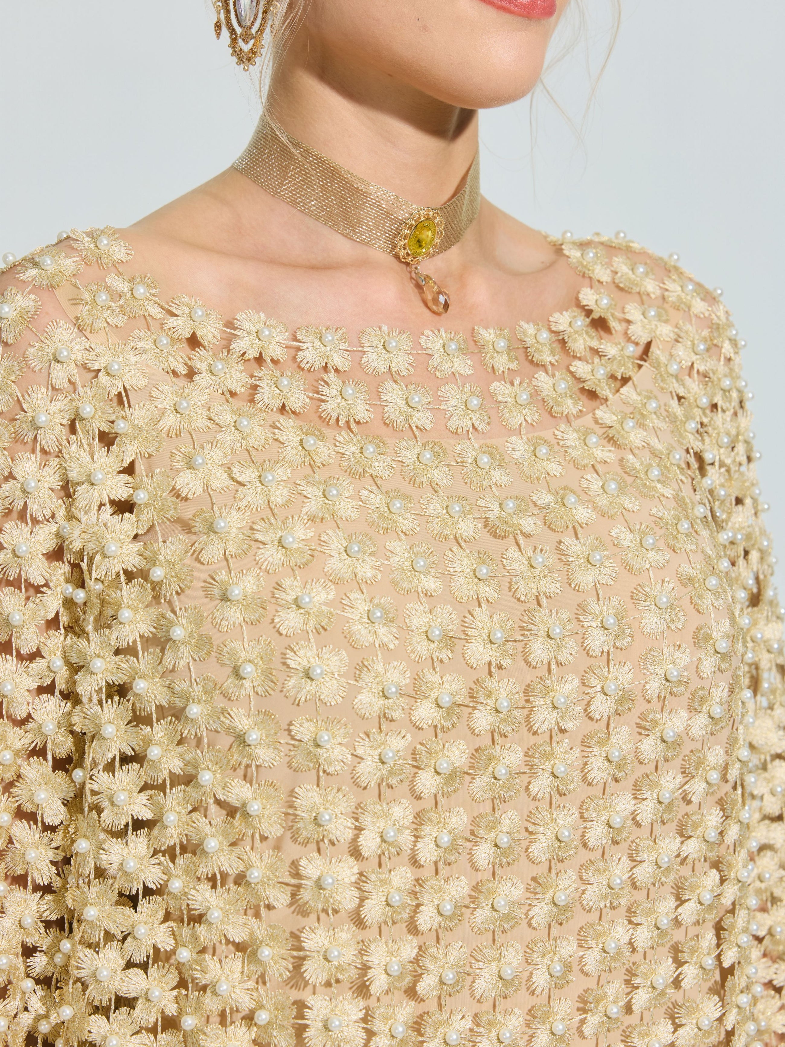A person wears the Social Queen Pearl Embellished Floral Overlay Dress with 3D floral appliqués and pearl accents, styled with a gold choker necklace featuring a small yellow gemstone.