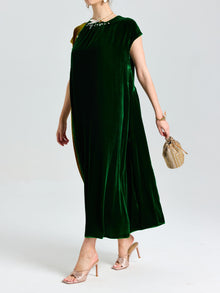 Wearing the Social Queen Colorblock Silk Velvet Shift Dress, with a beaded neckline and heeled sandals, she holds a small woven handbag against a plain background.