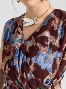 A person wearing the Social Queen Floral Print Fringe Tie-Front Top and a gold necklace with a white bird and flower pendant.