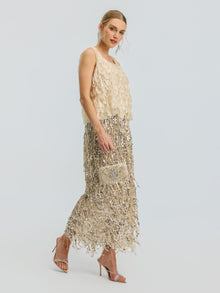 A woman in the Social Queen 3D Leaf Beaded Mesh Top, styled with a small embellished clutch and sandals, stands against a plain light background.