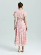 A woman faces away, wearing the Social Queen Floral Embroidered Lace Dress in light pink with short sleeves and lace-up back detail, paired with nude heeled sandals.