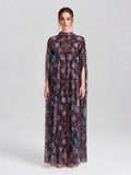 A woman poses in a studio wearing the Social Queen Beaded Floral Embellished Cape Gown—an elegant long, sheer purple gown with floral sequins and short sleeves—set against a neutral background.