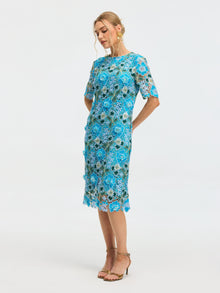 A woman stands in profile against a plain white background wearing the Social Queen Floral Appliqué Lace Shift Dress with short sleeves and tan high-heeled sandals.
