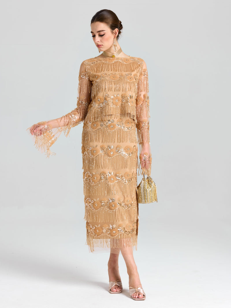 A woman wears the Social Queen Beaded Fringe Floral Top, paired with a small gold handbag and open-toe heels, standing against a plain background.