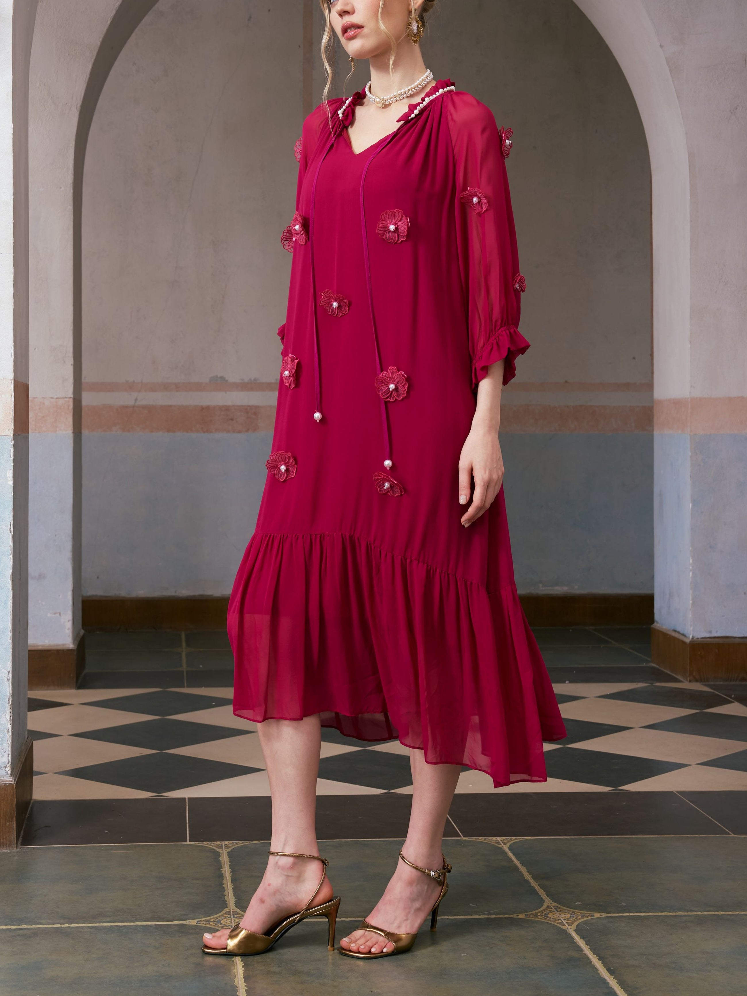 A person wearing the Social Queen 3D Floral Pearl Mulberry Silk Dress in magenta with gold heels stands indoors in front of an arched doorway.