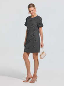 Woman in the Social Queen Beaded Floral Appliqué Dress, paired with a chic beige mini handbag and clear high-heeled sandals—an elegant occasionwear look for any special event.