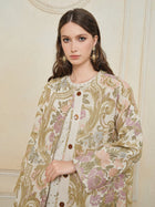 A woman with long brown hair wears the Social Queen Italian Baroque Floral Metallic Jacquard Jacket with large buttons and ornate earrings, standing against a textured cream-colored wall.