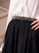 A person in a white blouse and the Social Queen Jacquard Lace A-Line Midi Skirt, styled with a multicolored beaded belt.
