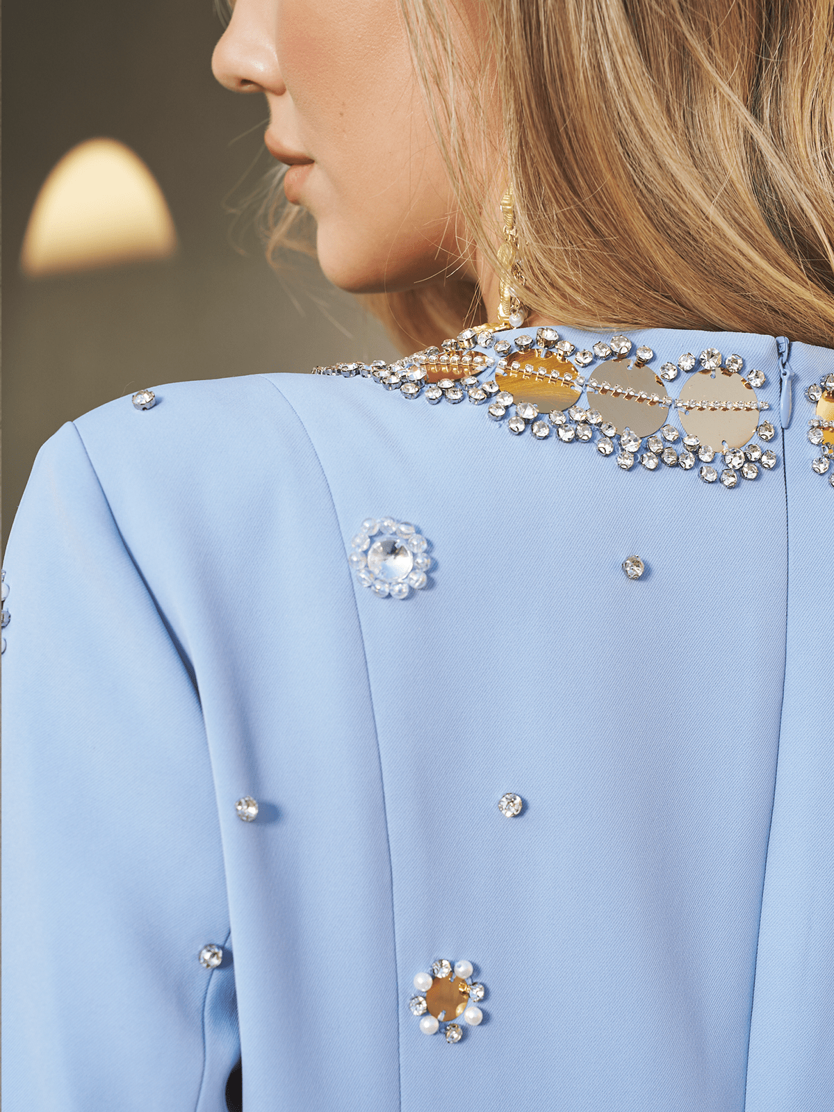 Close-up of a woman in the Social Queen Jewel-Beaded Gold-Trim Dress, featuring shimmering hand-beaded jewels and elegant gold accents, her blonde hair gracefully draped over her shoulder.