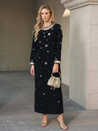 A woman stands on a stone floor in the Social Queen Jewel-Beaded Gold-Trim Dress with gold sandals, a woven handbag, and jewelry.