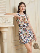 A woman wears the Social Queen Jewel-Embellished Floral Mini Dress, standing by an ornate mantel with a small gold handbag and statement earrings.