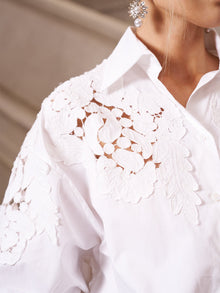 Close-up of the Social Queen Lace Appliqué Shirt, featuring intricate floral embroidery on the shoulder and upper chest for effortless elegance; a dangling earring adds a subtle accent.