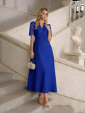 A woman in a royal blue Social Queen Lace-Panel Satin A-Line Gown stands on a staircase, accessorized with a silver handbag, silver sandals, and statement earrings.