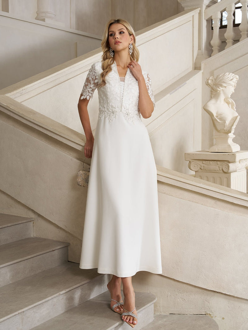 A woman in the Social Queen Lace-Panel Satin A-Line Gown stands on a staircase beside a classical statue in an elegant, light-toned interior.