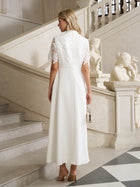 A woman in the Social Queen Lace-Panel Satin A-Line Gown stands on a marble staircase, holding a small purse, surrounded by statues and ornate railings.