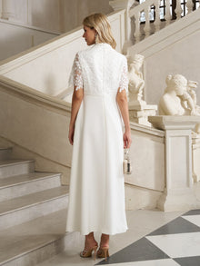 A woman in the Social Queen Lace-Panel Satin A-Line Gown stands on a marble staircase, holding a small purse, surrounded by statues and ornate railings.