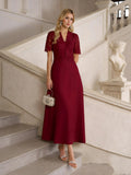 A woman stands on an elegant staircase in the Social Queen Lace-Panel Satin A-Line Gown, styled with a small silver handbag and strappy sandals.