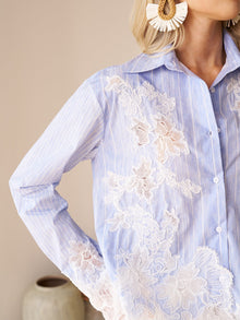 Someone wears the Social Queen Lace Panel Striped Cotton Blouse with large statement earrings. A ceramic vase is in the background.
