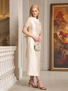 A woman in the Social Queen Lace-Trim Satin Midi Dress stands indoors, holding a small embellished handbag beside a classical painting.
