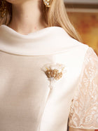 Close-up of a woman wearing the Social Queen Lace-Trim Satin Midi Dress in cream, featuring heavyweight satin fabric, lace cape sleeves, and a beaded floral brooch on the chest.