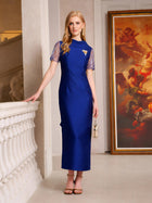 A woman in the Social Queen Lace-Trim Satin Midi Dress stands indoors next to a white railing and large framed painting, holding a small purse.