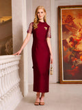 A woman in the Social Queen Lace-Trim Satin Midi Dress stands indoors near a staircase and large framed painting, holding a small handbag.
