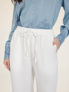 A person wearing Social Queen Linen Straight-Leg Pants with a breathable texture and one hand in their pocket, paired with a light blue button-up shirt featuring lace details.